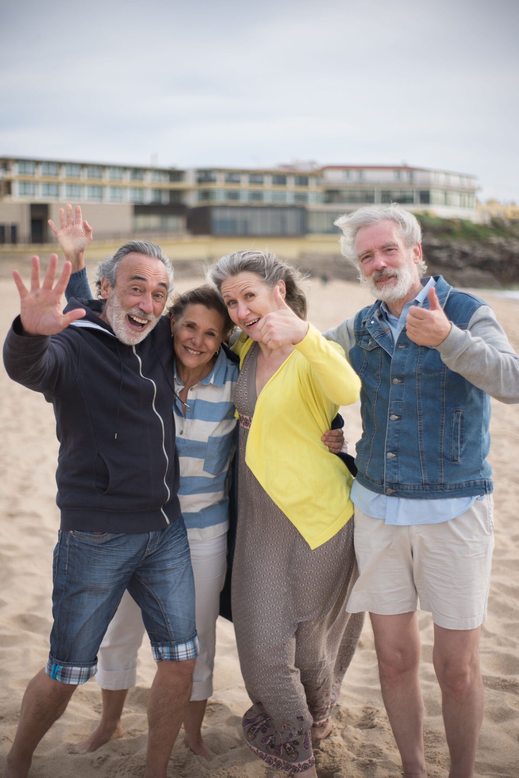 Group of joyful senior friends posing on a sunny beach in Portugal, capturing happy vacation memories together.